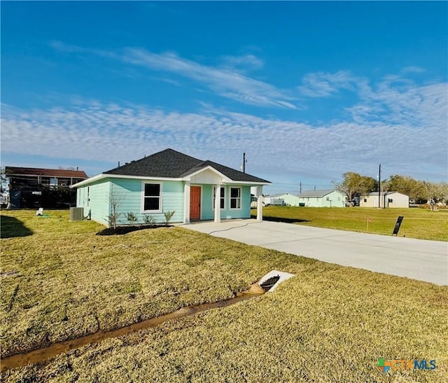 view of front of property featuring concrete driveway, a front lawn, and central AC