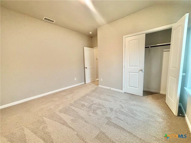 unfurnished bedroom with carpet floors, a closet, visible vents, and baseboards