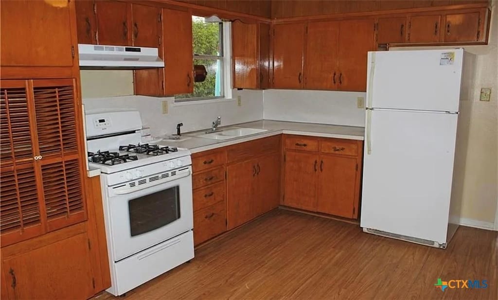 511 Louise St, Copperas Cove, TX 76522 - kitchen with white appliances, under cabinet range hood, light countertops, light wood-style flooring, and brown cabinets