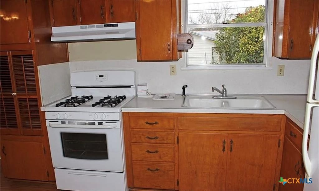 511 Louise St, Copperas Cove, TX 76522 - kitchen with under cabinet range hood, white gas stove, light countertops, and brown cabinetry