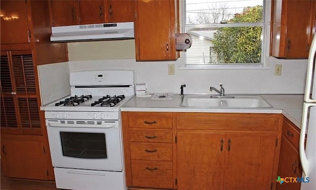 511 Louise St, Copperas Cove, TX 76522 - kitchen with under cabinet range hood, white gas stove, light countertops, and brown cabinetry
