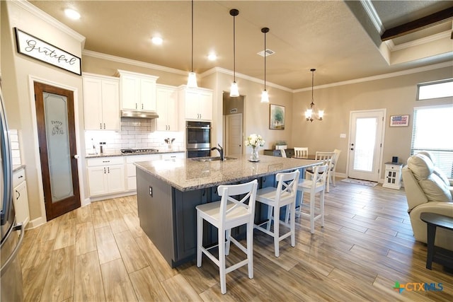 kitchen featuring a breakfast bar area, light wood-style flooring, under cabinet range hood, and stainless steel appliances