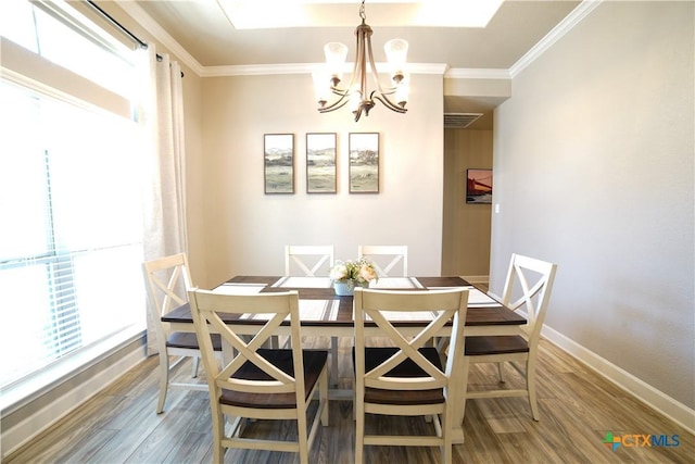 dining room with a chandelier, ornamental molding, baseboards, and wood finished floors