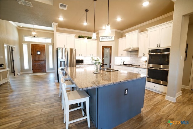 kitchen with under cabinet range hood, visible vents, stainless steel appliances, and a sink