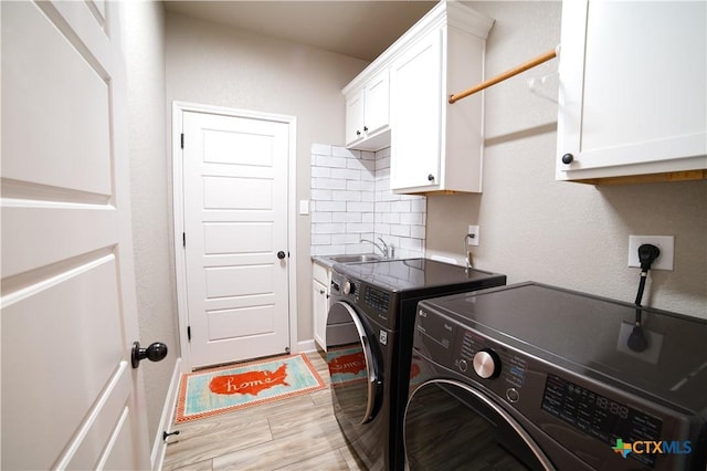 laundry area featuring washer and clothes dryer, cabinet space, light wood-type flooring, and a sink