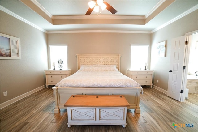 bedroom with ornamental molding, a raised ceiling, and wood finished floors