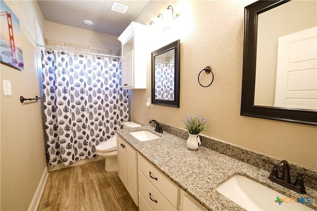 bathroom with toilet, wood finished floors, visible vents, and a sink