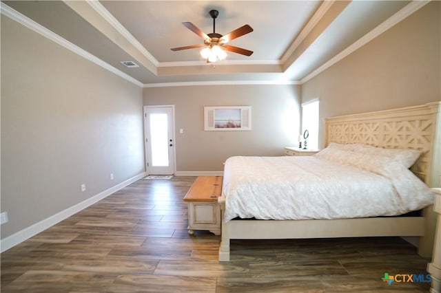 bedroom with visible vents, dark wood-type flooring, baseboards, crown molding, and a raised ceiling