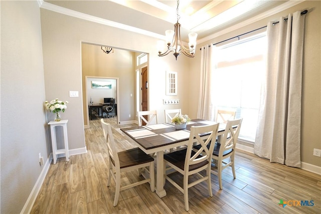 dining room featuring a chandelier, crown molding, light wood-type flooring, and baseboards