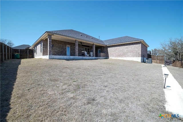 rear view of property featuring a fenced backyard, brick siding, and ceiling fan