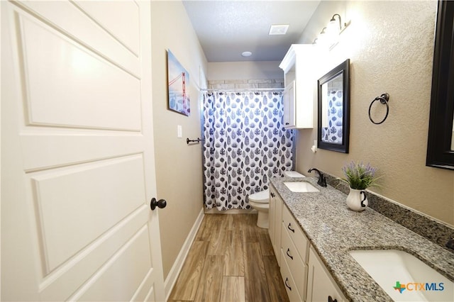 full bath with double vanity, wood finished floors, toilet, and a sink