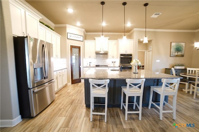 kitchen with visible vents, white cabinetry, stainless steel appliances, light wood finished floors, and decorative backsplash