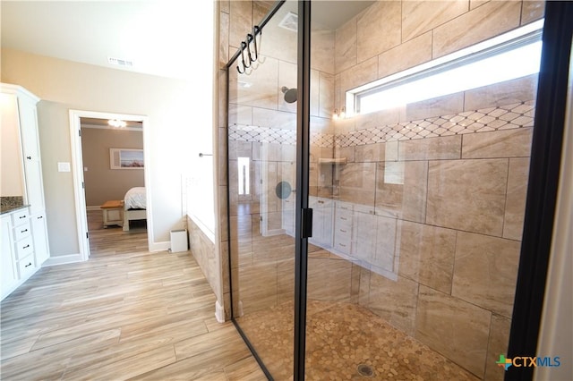 full bathroom with vanity, wood finished floors, baseboards, a stall shower, and ensuite bathroom