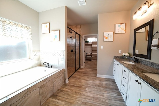 bathroom featuring visible vents, plenty of natural light, a stall shower, a sink, and a garden tub