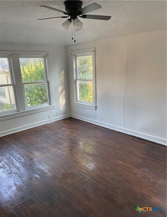 spare room with dark hardwood / wood-style flooring, a textured ceiling, and a healthy amount of sunlight