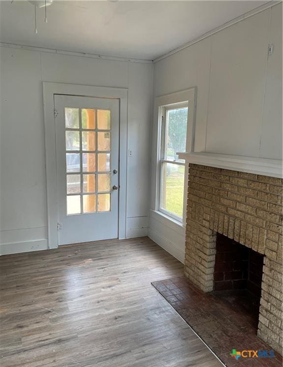 unfurnished living room featuring plenty of natural light, hardwood / wood-style floors, and a brick fireplace