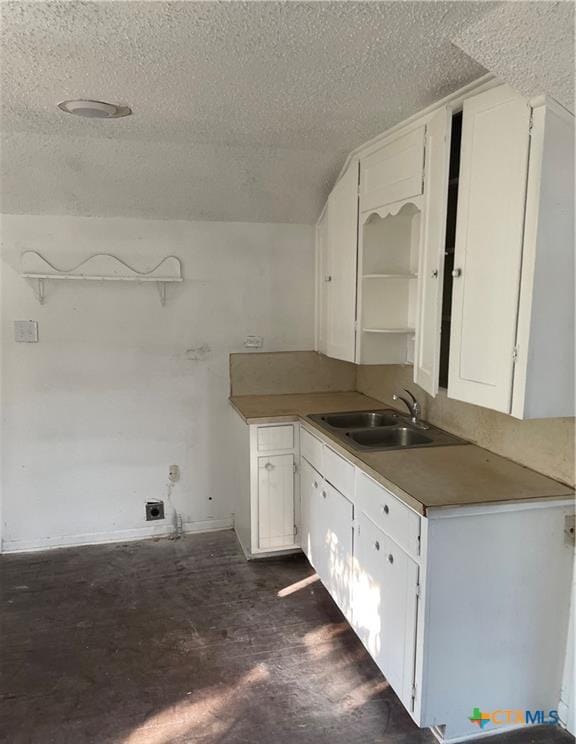 kitchen with white cabinetry, sink, dark wood-type flooring, and a textured ceiling