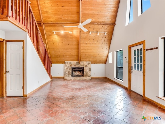 unfurnished living room with a stone fireplace, high vaulted ceiling, ceiling fan, and wood ceiling