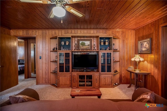 carpeted living room featuring wood ceiling, ceiling fan, and wooden walls