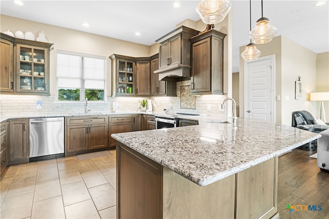 kitchen featuring light stone countertops, a peninsula, stainless steel appliances, and tasteful backsplash