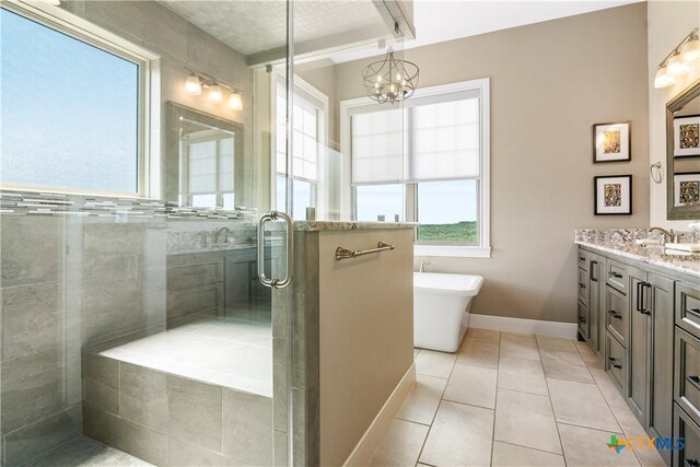 full bathroom with tile patterned flooring, vanity, baseboards, a soaking tub, and a stall shower