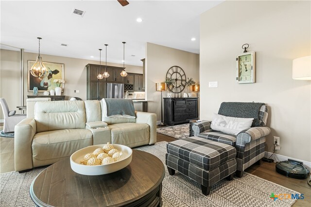 living area featuring wood finished floors, ceiling fan with notable chandelier, baseboards, visible vents, and recessed lighting