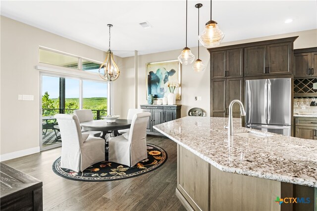 kitchen featuring visible vents, dark brown cabinets, a sink, backsplash, and freestanding refrigerator