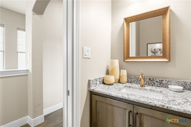bathroom featuring baseboards, wood finished floors, and vanity