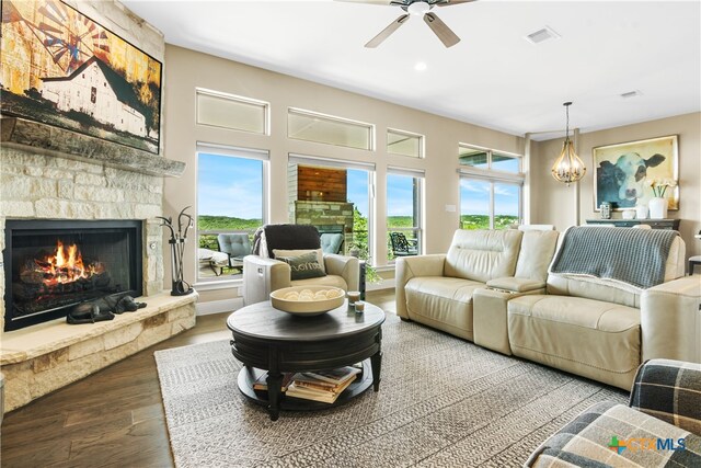 living room featuring wood finished floors, ceiling fan with notable chandelier, a fireplace, and visible vents