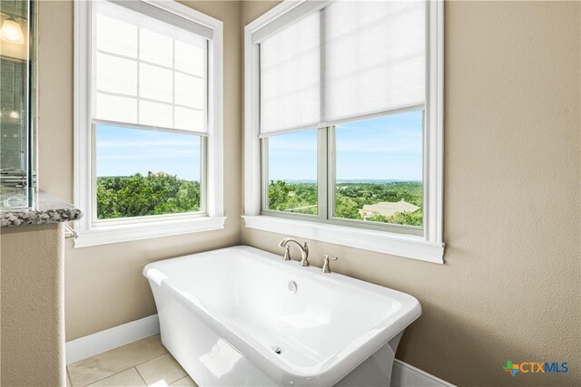 full bathroom featuring a soaking tub, tile patterned flooring, and baseboards