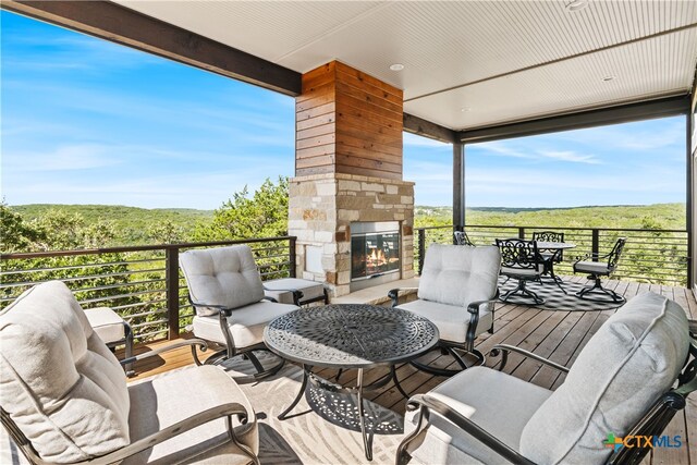 deck featuring an outdoor living space with a fireplace and a view of trees