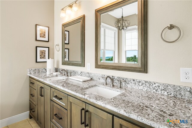 bathroom featuring double vanity, a notable chandelier, a sink, and tile patterned floors