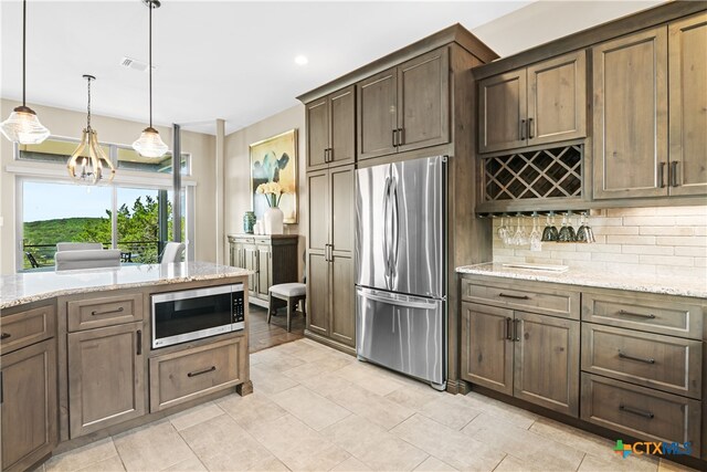 kitchen featuring a notable chandelier, light stone counters, tasteful backsplash, appliances with stainless steel finishes, and visible vents