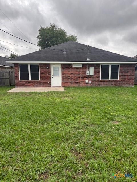 back of house featuring fence, a patio, brick siding, and a lawn
