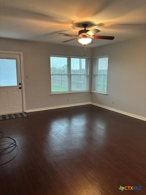 interior space featuring baseboards, a healthy amount of sunlight, dark wood finished floors, and ceiling fan