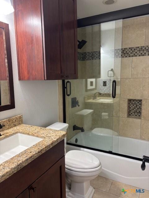 bathroom featuring vanity, toilet, bath / shower combo with glass door, and tile patterned flooring