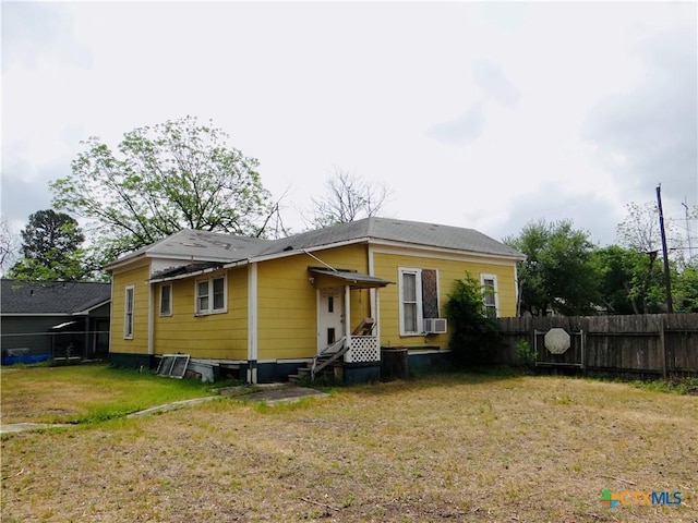 back of house with cooling unit, a lawn, and fence