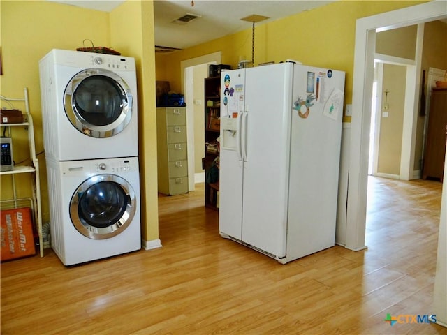 laundry area featuring light wood-style floors, visible vents, stacked washer / dryer, and laundry area