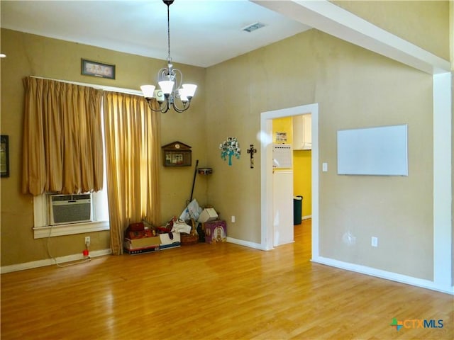 interior space featuring baseboards, a chandelier, cooling unit, and light wood-style floors