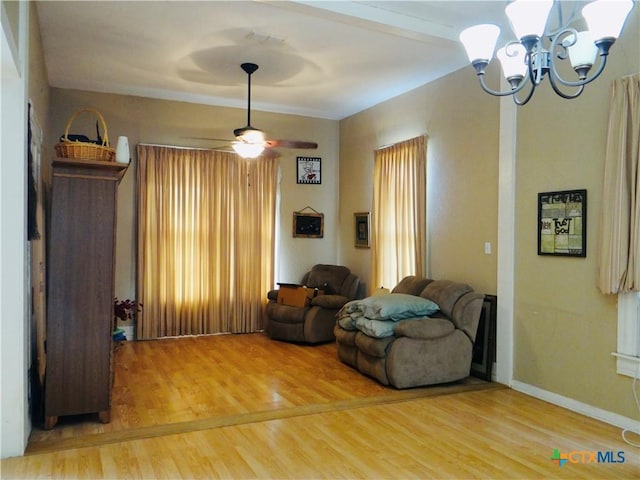 sitting room with baseboards, wood finished floors, a notable chandelier, and a healthy amount of sunlight