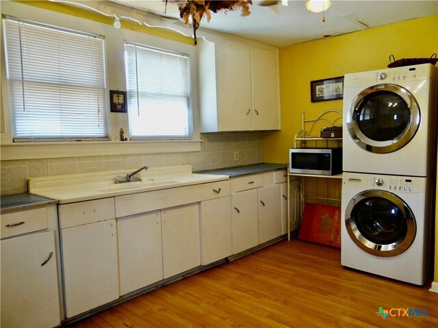 laundry area with a healthy amount of sunlight, stacked washer and clothes dryer, laundry area, and a sink