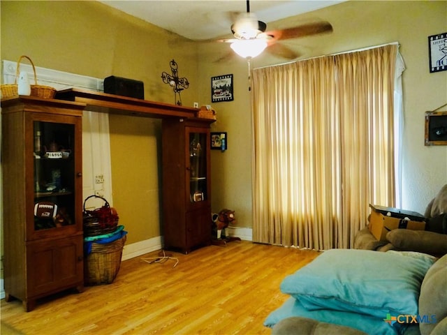 interior space featuring light wood finished floors, baseboards, and a ceiling fan