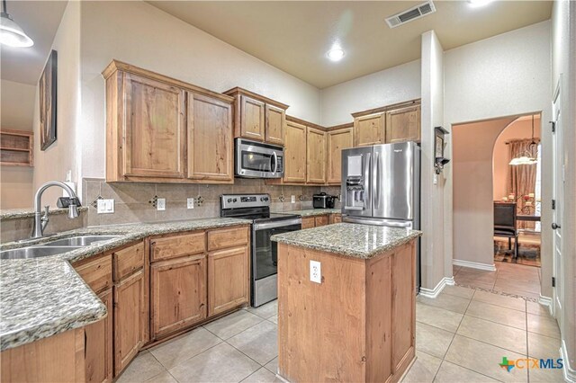 4813 Sapphire Dr, Killeen, TX 76542 - kitchen featuring appliances with stainless steel finishes, a sink, light tile patterned floors, a kitchen island, and tasteful backsplash