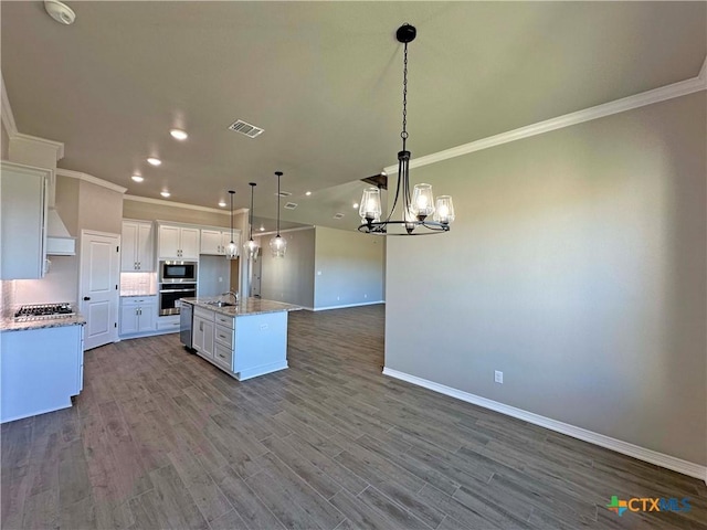 kitchen with appliances with stainless steel finishes, light hardwood / wood-style flooring, white cabinetry, hanging light fixtures, and an island with sink