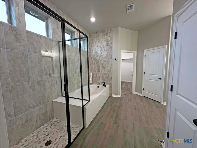 bathroom with hardwood / wood-style flooring and independent shower and bath