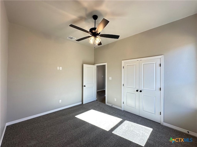 unfurnished bedroom featuring dark colored carpet, a closet, and ceiling fan