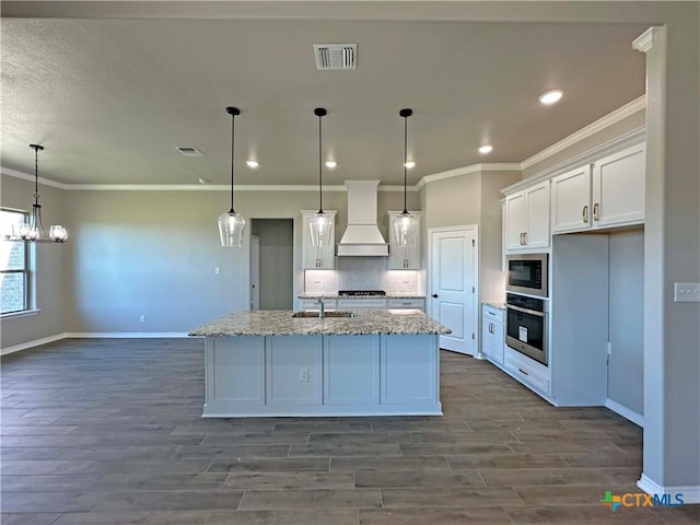 kitchen with built in microwave, stainless steel oven, pendant lighting, white cabinets, and custom range hood