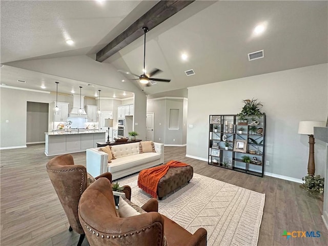 living room featuring dark wood-type flooring, vaulted ceiling with beams, and ceiling fan