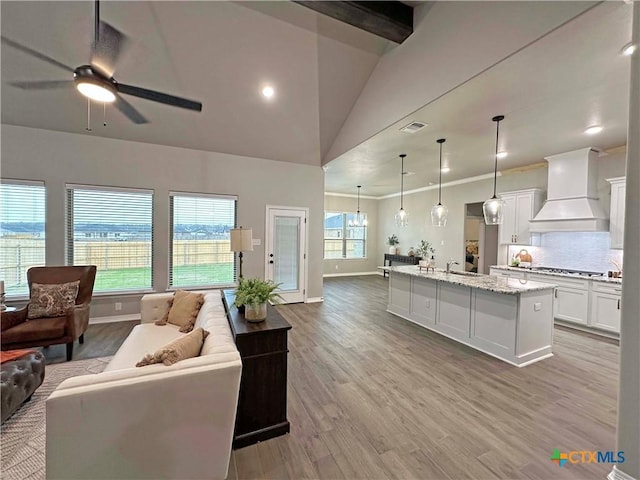 living room with light wood-type flooring, a wealth of natural light, ceiling fan, and ornamental molding