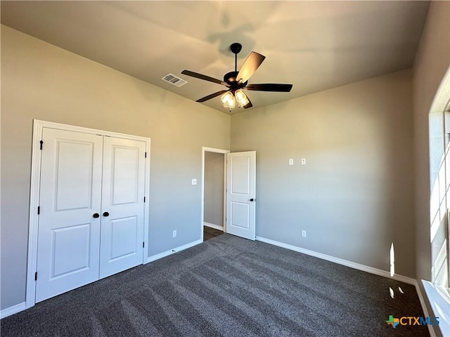 unfurnished bedroom with ceiling fan, a closet, and dark colored carpet